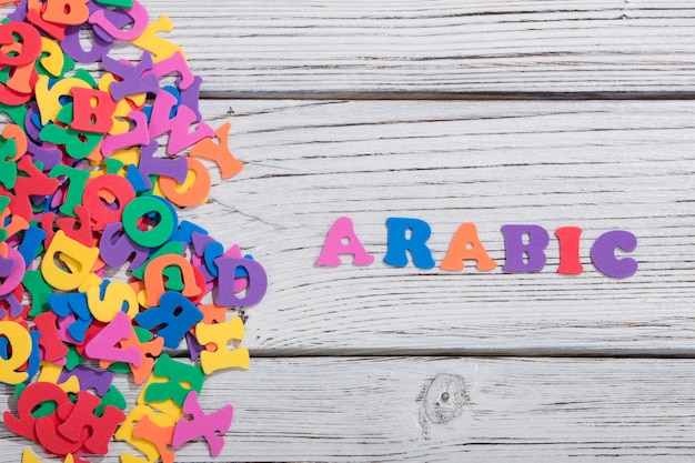 The colorful words arabic made with colorful letters over white wooden board