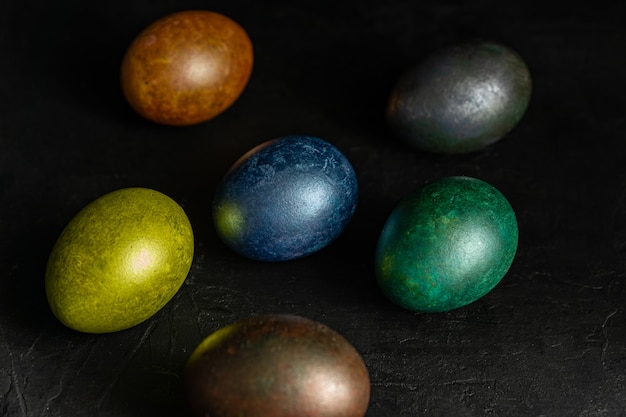 Colorfull marble painted easter eggs on black background. Concept of minimal festive Easter backdrop.