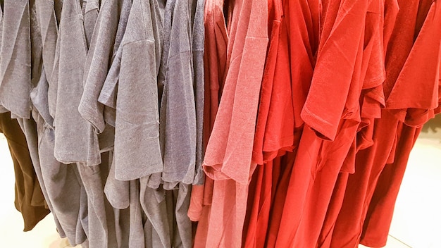 Colors of rainbow. Variety of casual shirts, t-shirts on hangers in a store. Cloth cotton of various bright colors close-up. Textile background.