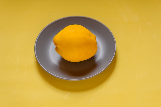 Colors of the year 2021. quince in a gray plate on a yellow background. Fruit