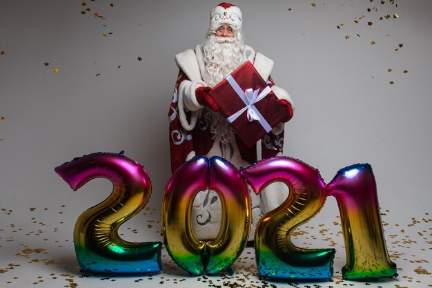 Colourful balloons in shape of 2021 and Santa with gift celebrating xmas and new year