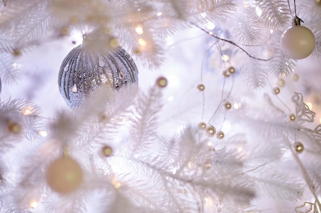 Colourful christmas decorations hanging from white christmas tree. white Christmas tree.