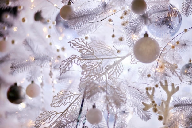 Colourful christmas decorations hanging from white christmas tree. white Christmas tree.