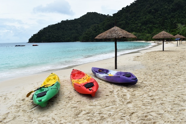 Colourful of kayaks stand on a sandy beach in Vacation.