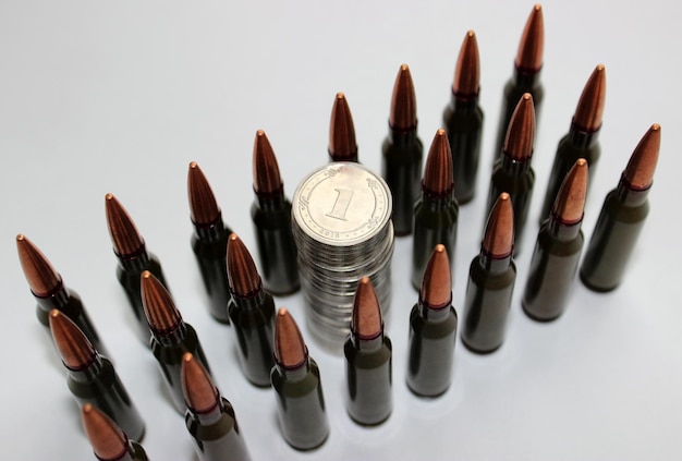 A column of silver coins between rows of live ammunition for an assault rifle