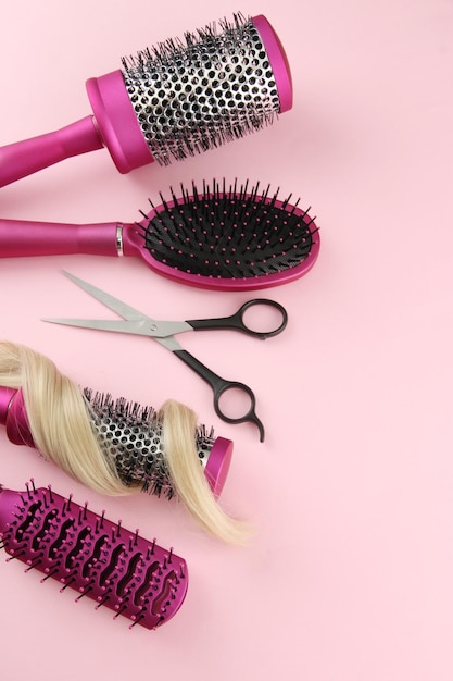 Comb brushes hair and cutting shears on pink background