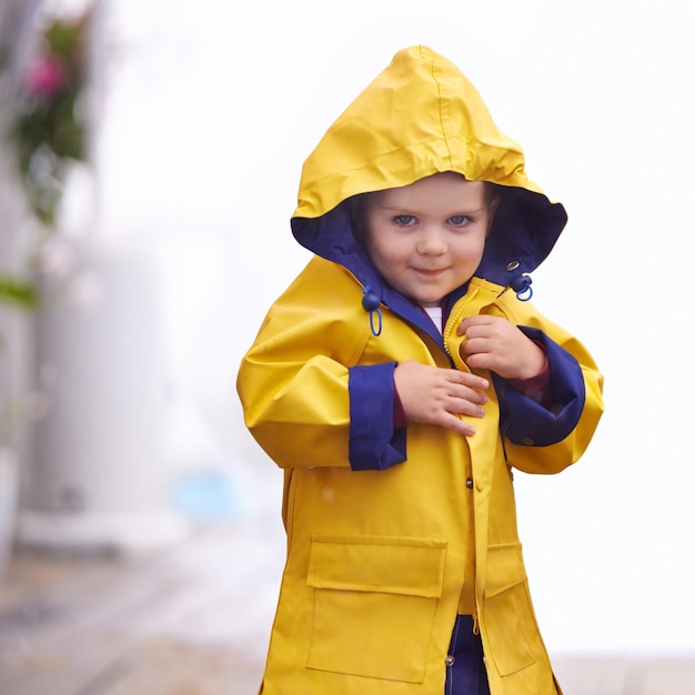 Photo come play in the rain shot of a young boy playing outside in the rain