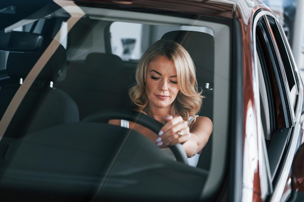 Comfortable car Woman in formal clothes is indoors in the autosalon