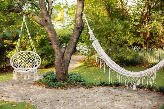 Comfortable hanging wicker white chair in summer garden