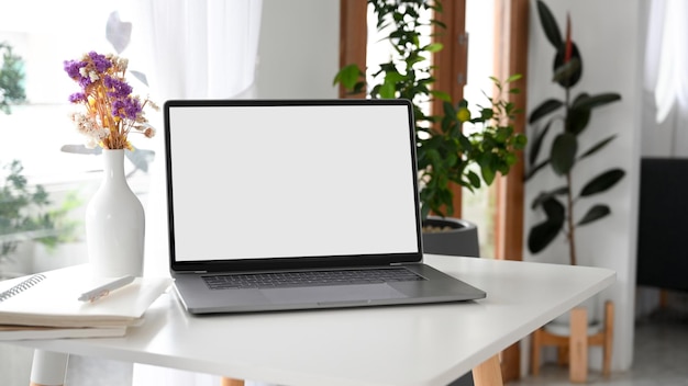 Comfortable and minimalist bright workspace with laptop computer mockup near the window