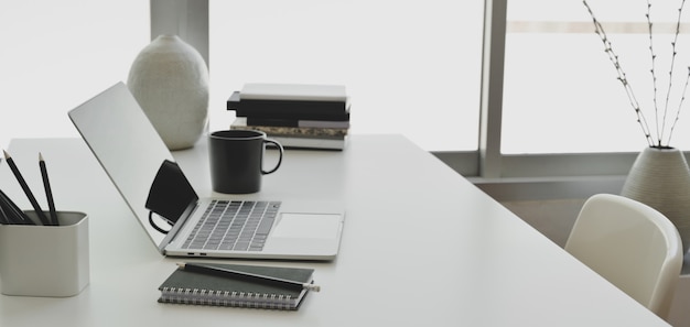 Comfortable office room with laptop computer and office supplies on white wooden table 