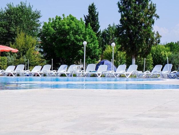 Comfortable sun loungers near swimming pool at resort