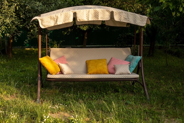 The comfortable swing with pillows in the backyard in summer