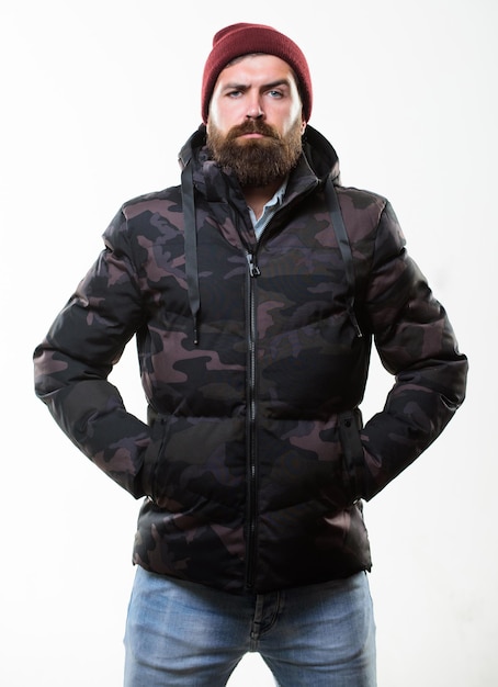 Comfortable winter outfit Man stand warm camouflage pattern jacket parka with hood isolated on white background Guy wear hat and black winter jacket Hipster winter fashion Winter stylish menswear