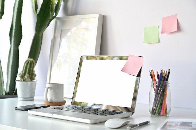 Comfortable working place in office with blank screen laptop on white wooden table