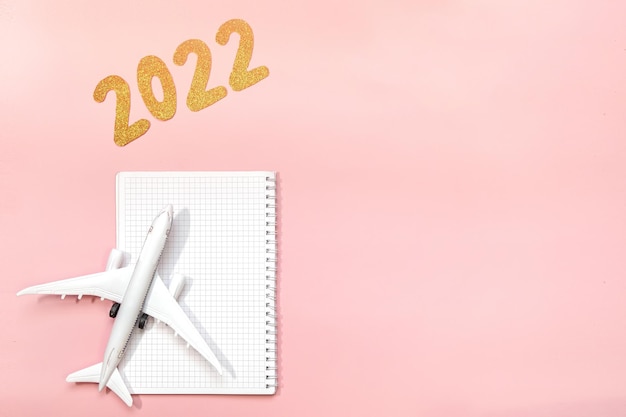 Coming 2022 text on pink background Flat lay design of work desk with Planning or notebook