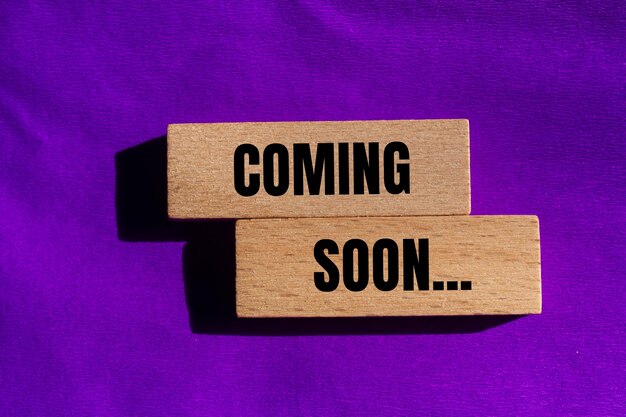 Photo coming soon message written on wooden blocks with purple background conceptual coming soon symbol copy space