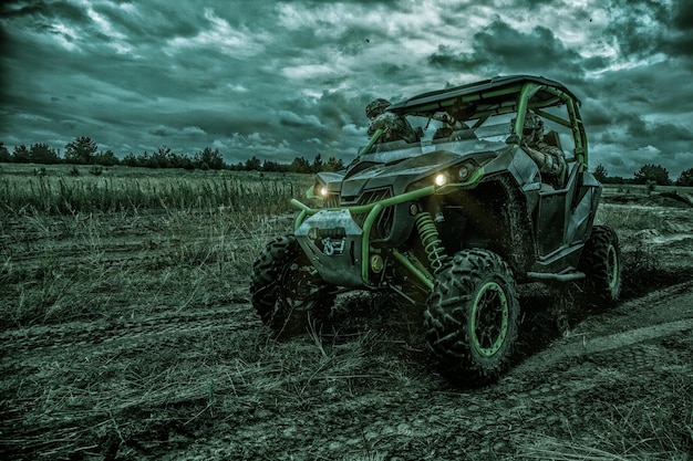 Commandos quick reaction group, special operations forces mobile team riding on fast attack vehicle or military sandrail during night patrolling in bad weather conditions. Raid under cover of darkness