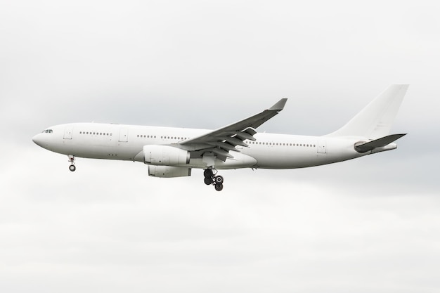 Commercial aircraft on approach before landing against cloudy sky.