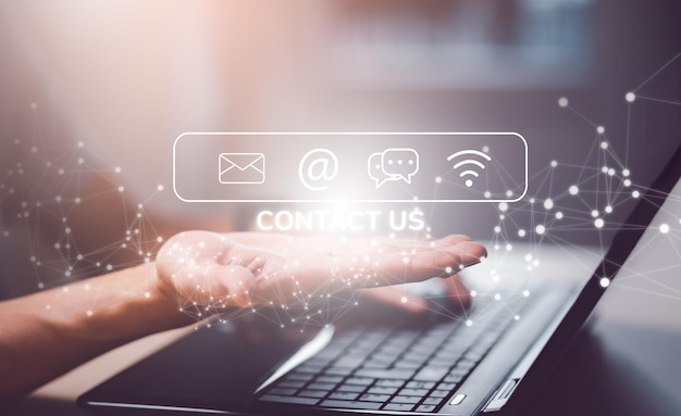 Communication and Contact us or Customer support hotline people connect. Hand using a laptop and touching on virtual screen contact icons, email and address, live chat with internet wifi.