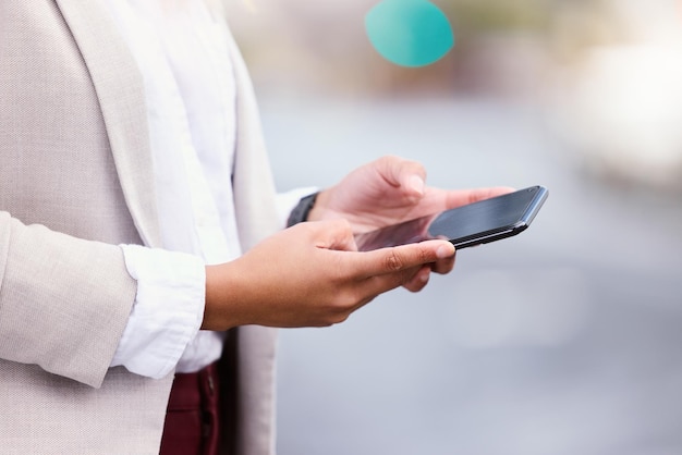 Communication is the key to success. Cropped shot of an unrecognizable young businesswoman texting while walking through the city.