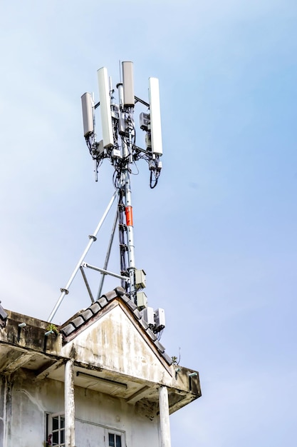 Communication tower with antennas on the top of building and bright blue sky background