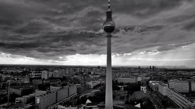 Communications tower in city against cloudy sky