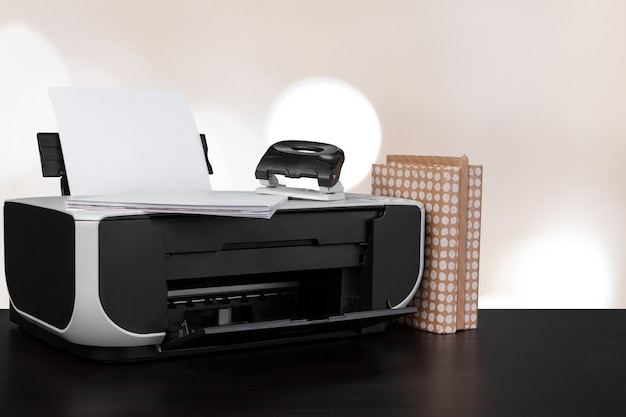 Compact home printer on desk with books against blurred background