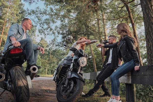 A company of friends travel together on motorcycles stopped at the roadside have fun and drink tea