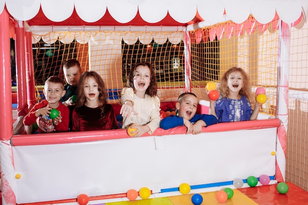 Company of happy children in the pool with colored balls. children's party.