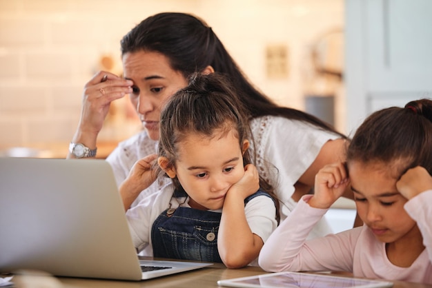 Compartmentalising time for herself and her kids. Shot of a young mother helping her daughters with their homework.