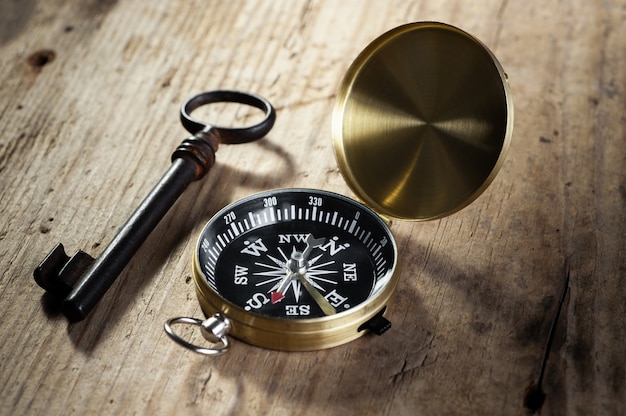 compass and antique key lie on a wooden