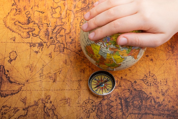 Compass beside a globe under hand as a concept of traveling