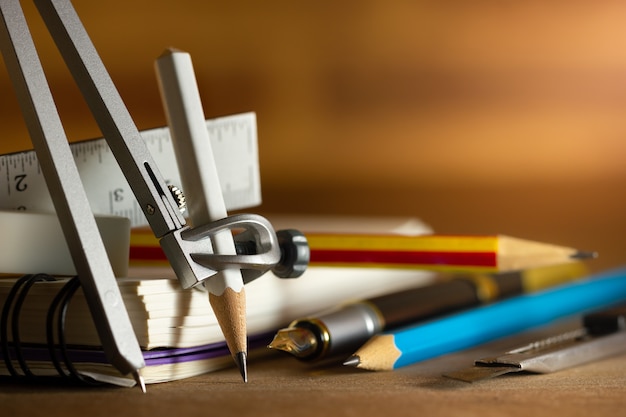 Compass for drawing and stationary on wooden table. Concept of architecture office or back to school. Closeup and copy space for text.