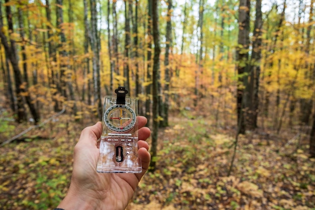 Compass in hand in the forest in autumn selective focus