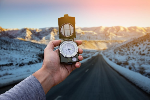 Compass in the hand of a man in snow road