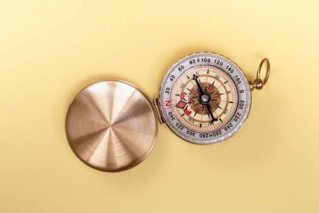 Compass on yellow background close up with copy space