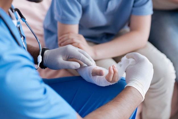 Competent pediatrician wearing rubber gloves while consulting his patient