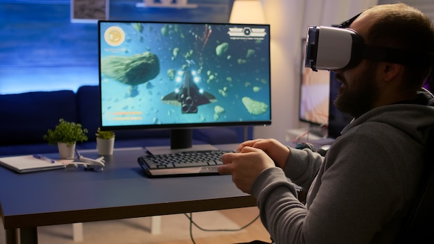 Photo competitive gamer winning space shooter video games championship wearing virtual reality goggles. pro cyber professional playing with joypad during online tournament using technology network wireless