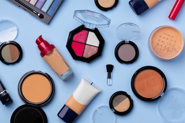 Complexion make up products and brush on blue background