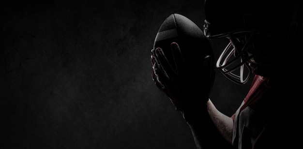 Composite image of american football player standing with rugby helmet and ball