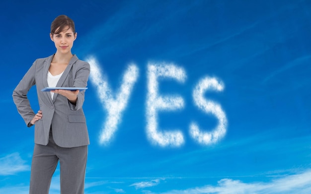 Composite image of attractive businesswoman holding tablet pc