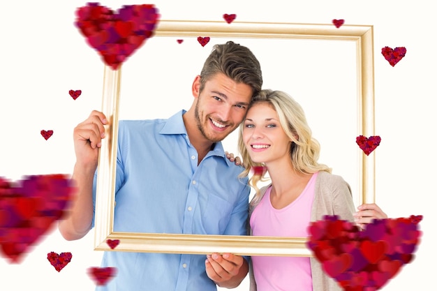 Composite image of attractive young couple holding picture frame