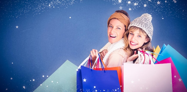 Composite image of beautiful women holding shopping bags looking at camera