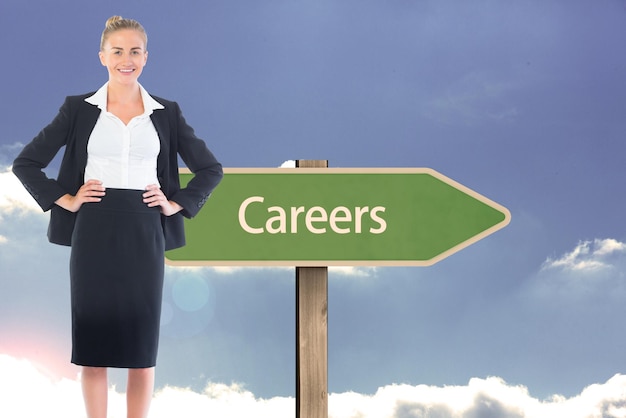 Composite image of blonde businesswoman standing with hands on hips