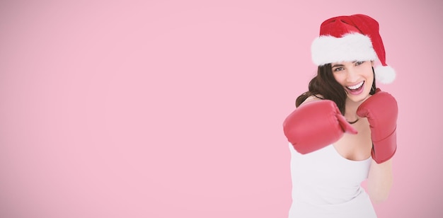 Composite image of festive brunette in boxing gloves punching