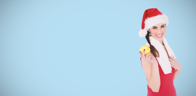 Composite image of festive fit brunette holding apple