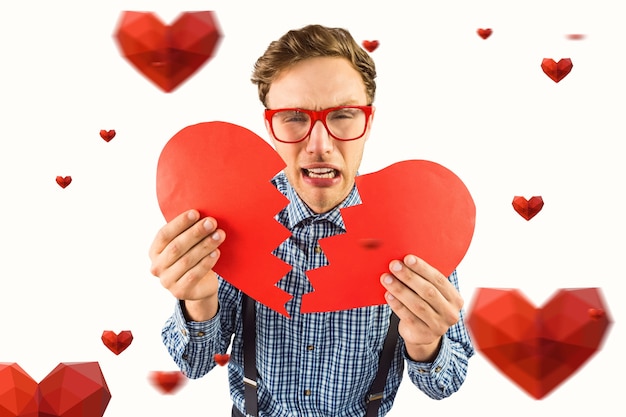 Composite image of geeky hipster holding a broken heart