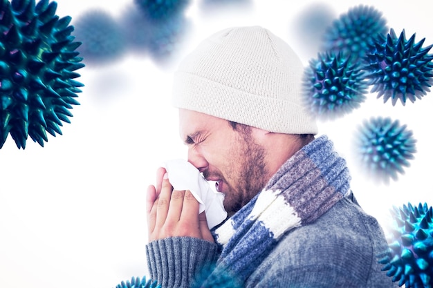 Composite image of handsome man in winter fashion blowing his nose