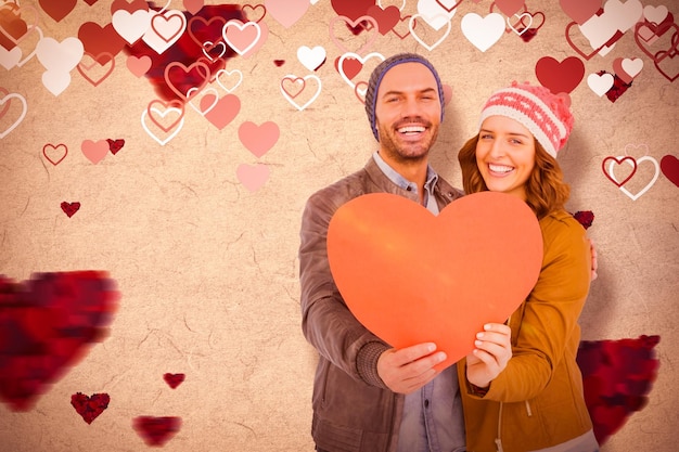 Composite image of happy young couple holding heart shape paper